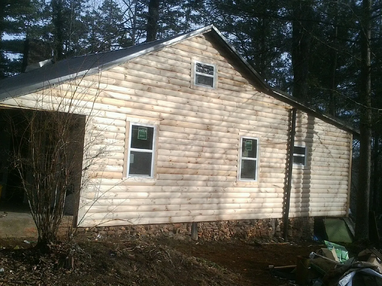 New log siding and dark metal roofing on a gable end in Ronkonkoma