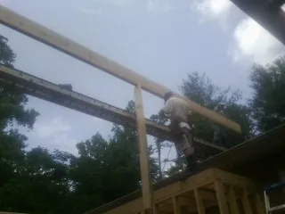 Carpenter setting a ridge beam over a new addition frame — Ice Dam Removal by Roofing Brothers in Ronkonkoma