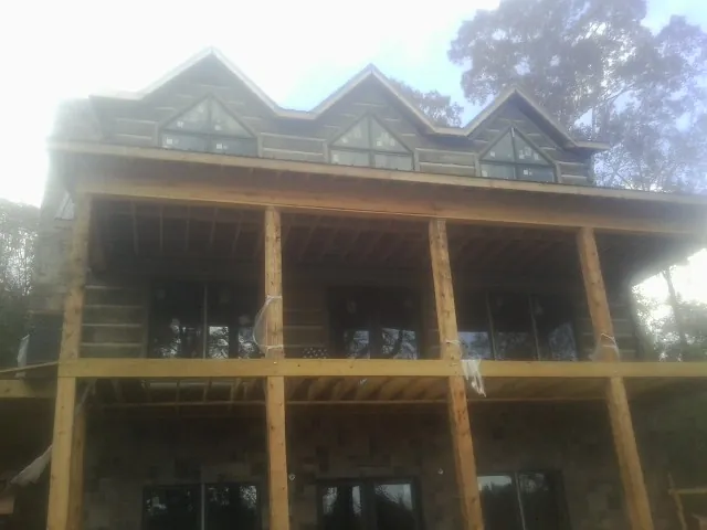 Dormers and porch framing on a large log home under construction — Roof Coating work by our crew in Ronkonkoma