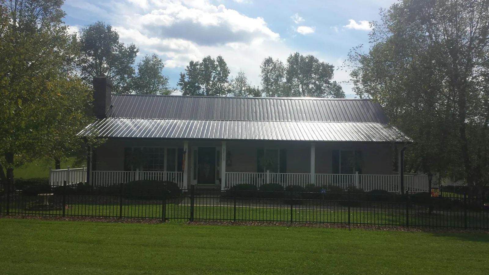 Gray metal roof on a brick ranch with a full width front porch — Gutter Guard Installation work by our crew in Ronkonkoma
