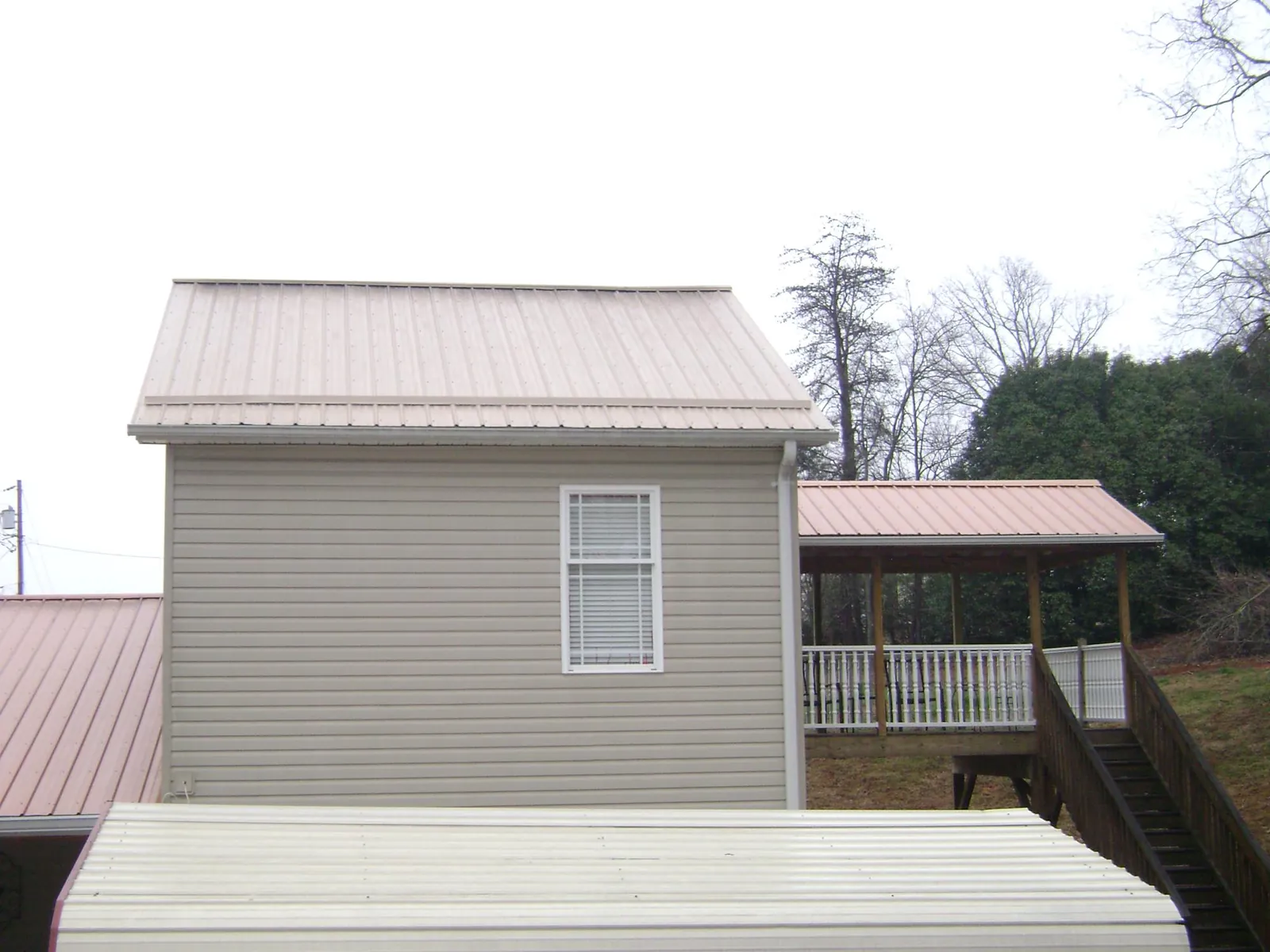 Tan metal roofs on a two story addition and attached porch, from a Roof Replacement job in Ronkonkoma