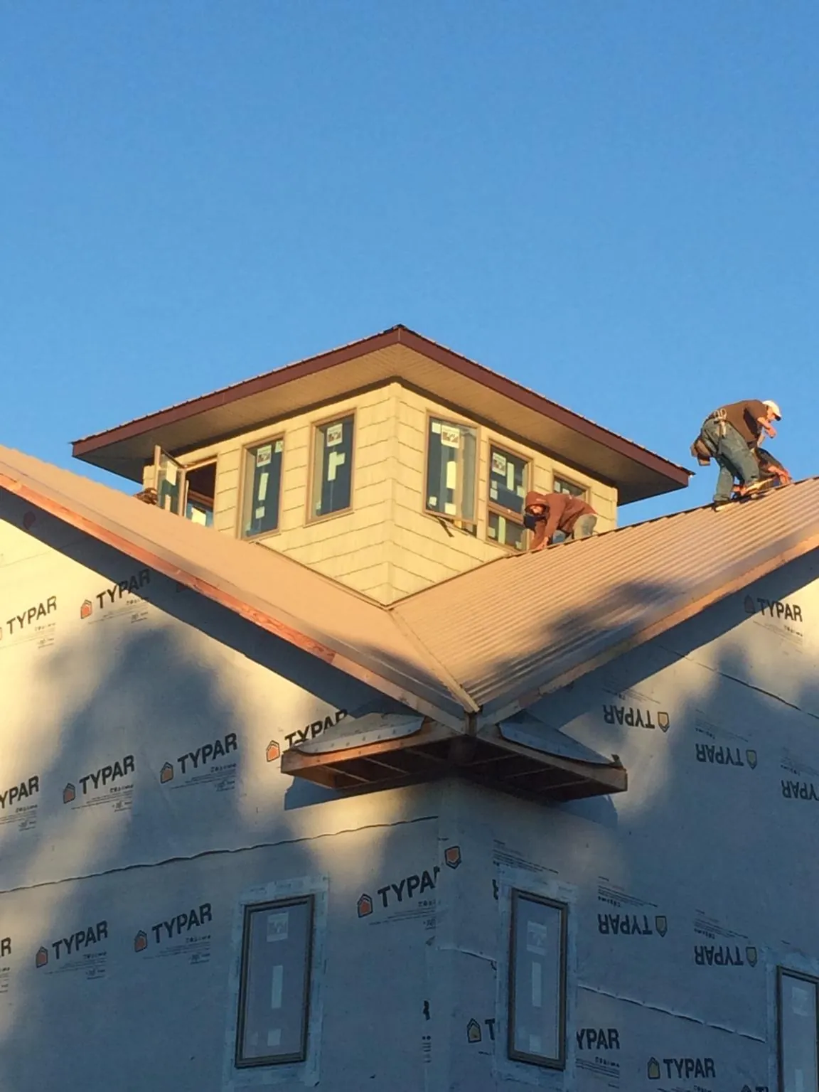 Roofers working around a rooftop cupola on a new metal roof at sunset — Roof Waterproofing in Ronkonkoma by Roofing Brothers